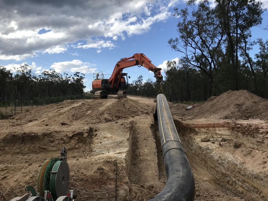 Excavator lowering pipeline into a trench on a FIFO worksite